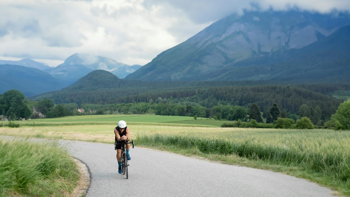Cycliste sur route de campagne sinueuse au cœur d'un paysage verdoyant