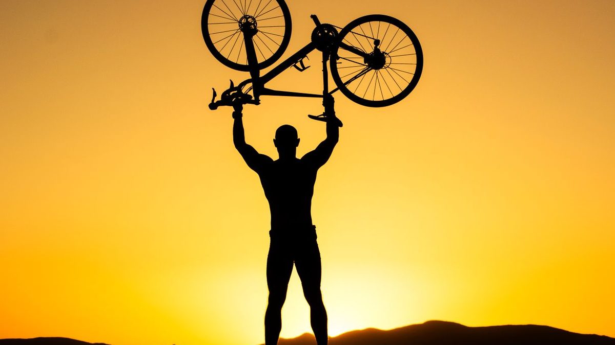 Cycliste brandissant son vélo au-dessus de la tête pour célébrer une victoire