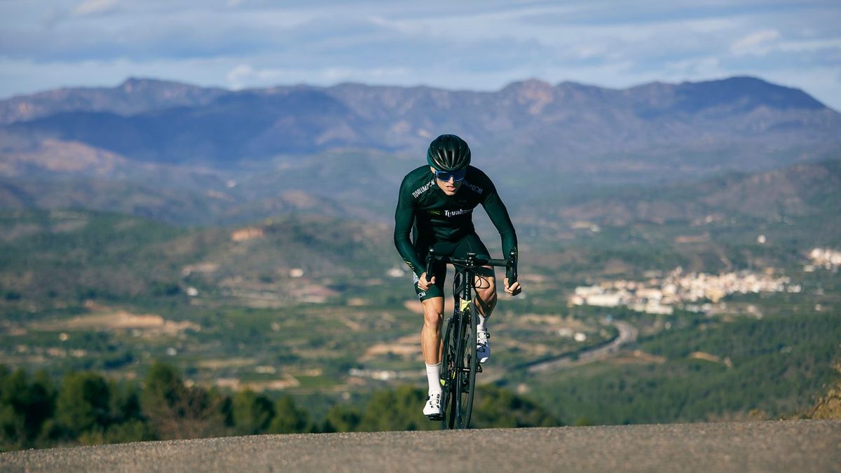Cycliste en danseuse gravissant une route de montagne sur un vélo de route carbone