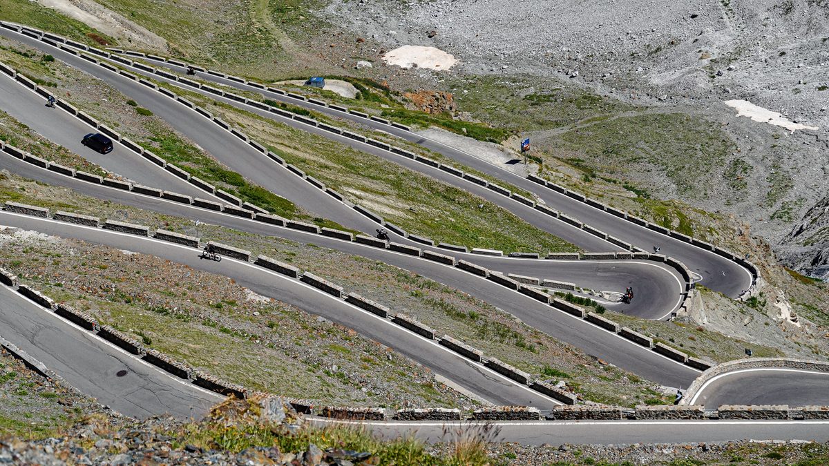 Vue aérienne d'une route de montagne en épingles avec des cyclistes, façon virages de l'Alpe d'Huez