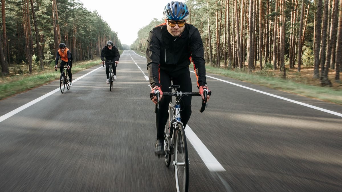 Groupe de cyclistes roulant sur une route forestière tranquille en vélo de route