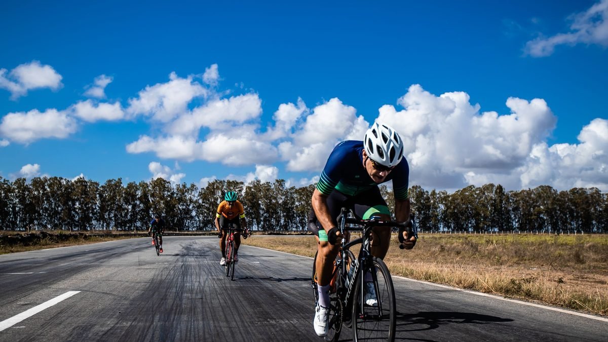 Cyclistes lancés à pleine vitesse sur une route ouverte en position aérodynamique