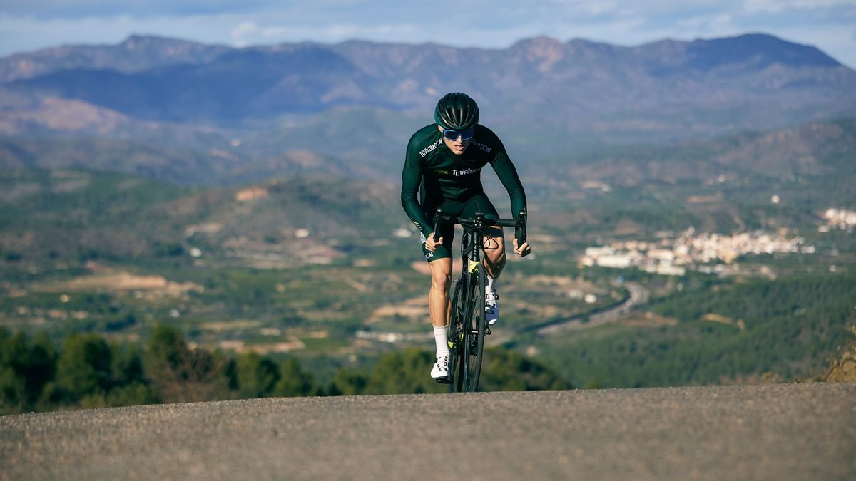 Cycliste en danseuse sur un vélo de route carbone haut de gamme, montagnes en arrière-plan